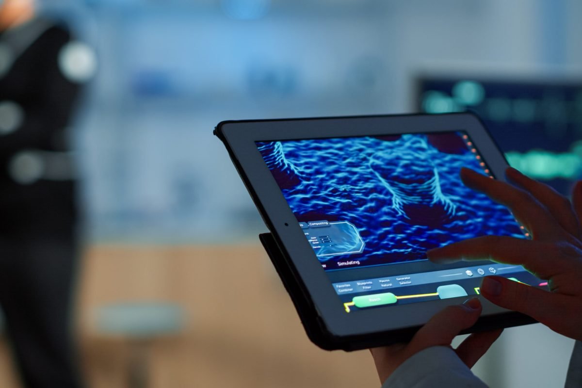 Close up of scientist analysing health informations in tablet while specialist sport supervises exercise of sportsman monitoring his physical endurance. Examining medical scan in notepad in laboratory